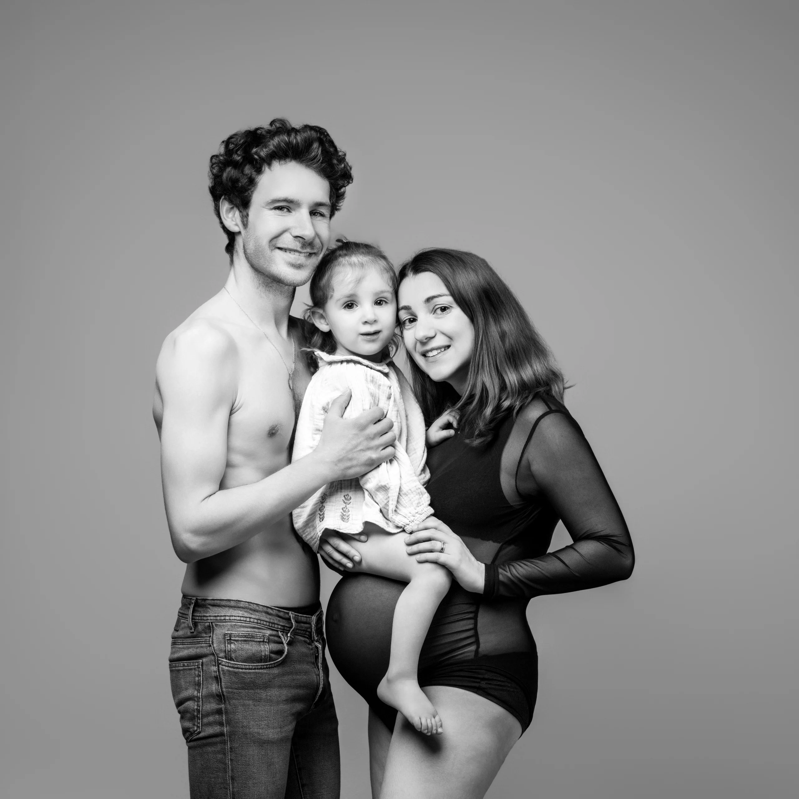 Couple avec enfant réalisant une séance photo grossesse en studio en noir et blanc