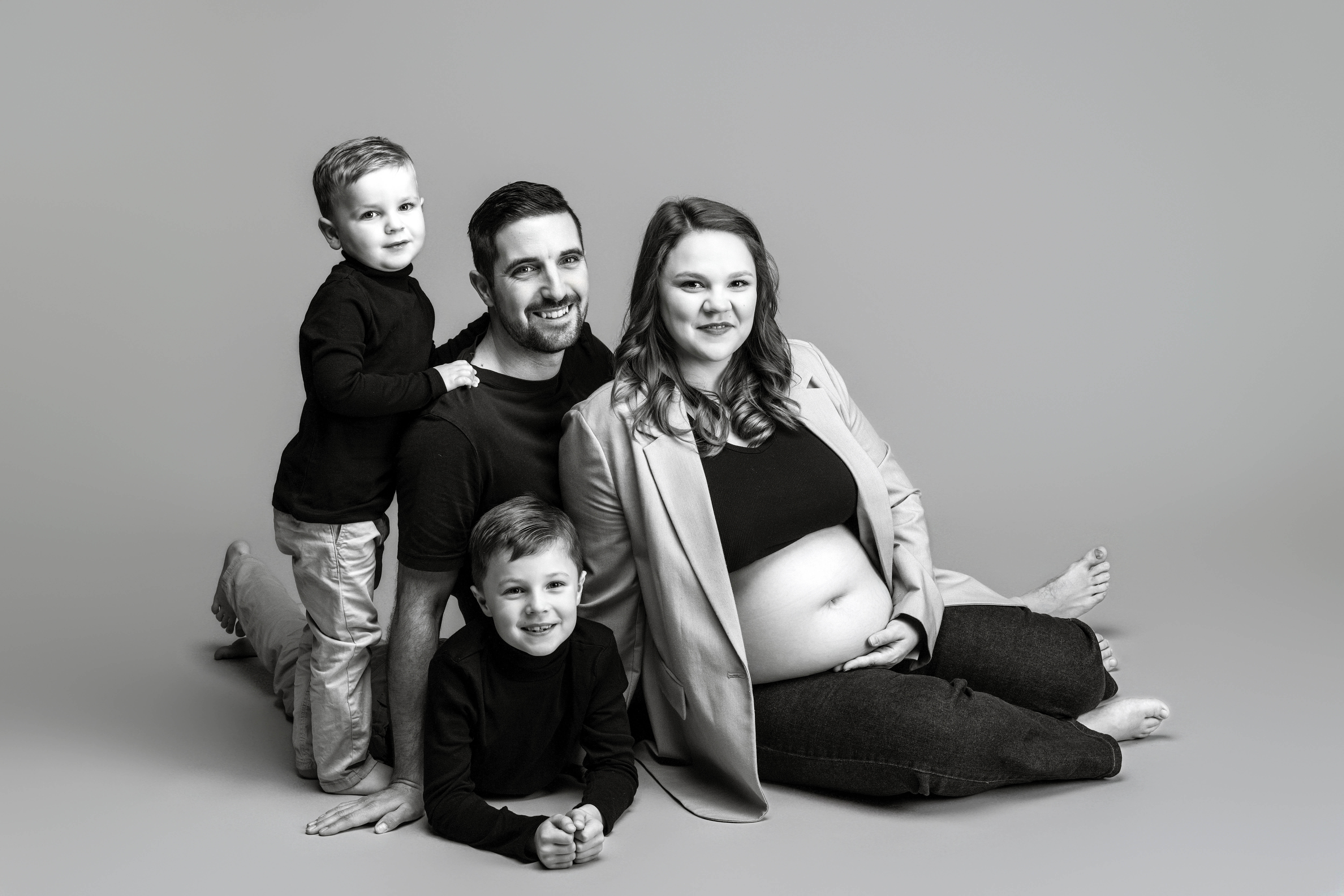 Famille avec deux enfants posant avec une femme enceinte en studio, photo noir et blanc à Rennes
