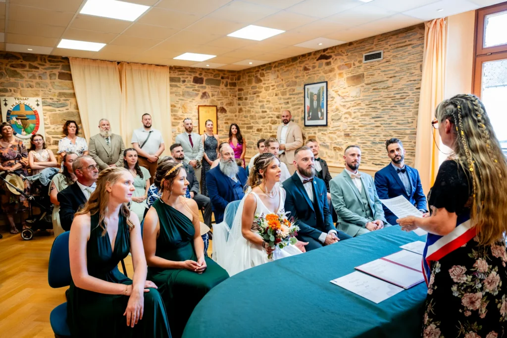 Cérémonie civile en mairie : l'élue en écharpe tricolore s'adresse aux mariés entourés de leurs témoins et invités, mariage en Ille-et-Vilaine.
